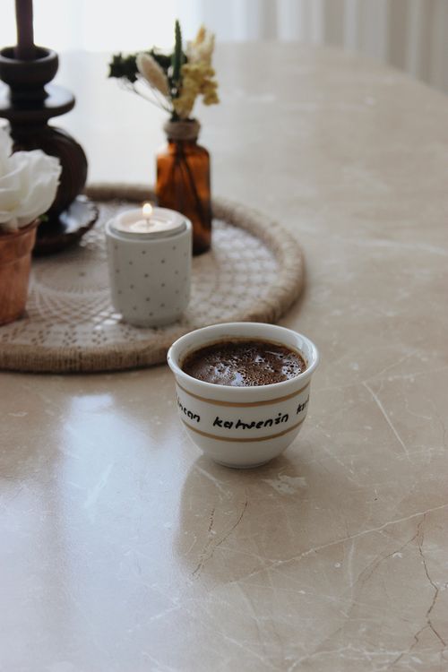 Free Warm coffee and candle on a marble table with a vase and flowers. Stock Photo