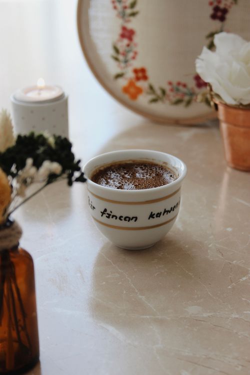 Free A serene close-up of Turkish coffee with decorative flowers and a lit candle on a marble table. Stock Photo