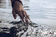 Close-Up Photo of a Person's Hand Touching Body of Water