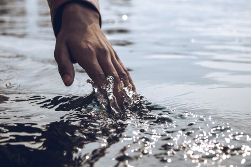 Close-up of a hand touching the surface of water