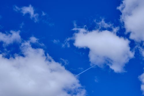 Free A vibrant blue sky with fluffy white clouds and a faint vapor trail in Threlkeld, UK. Stock Photo