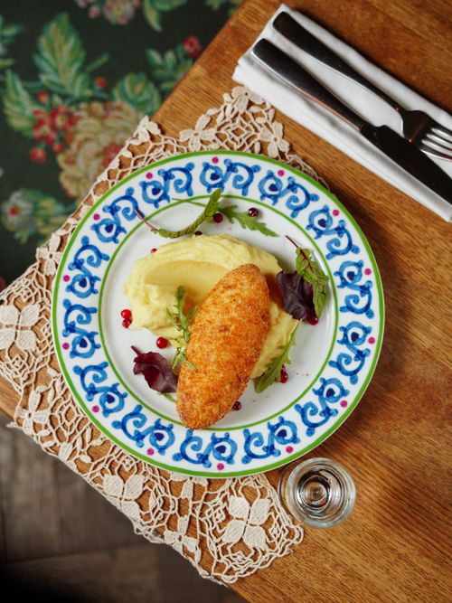 Free Appetizing Chicken Kiev with mashed potatoes and greens on a floral plate. Stock Photo
