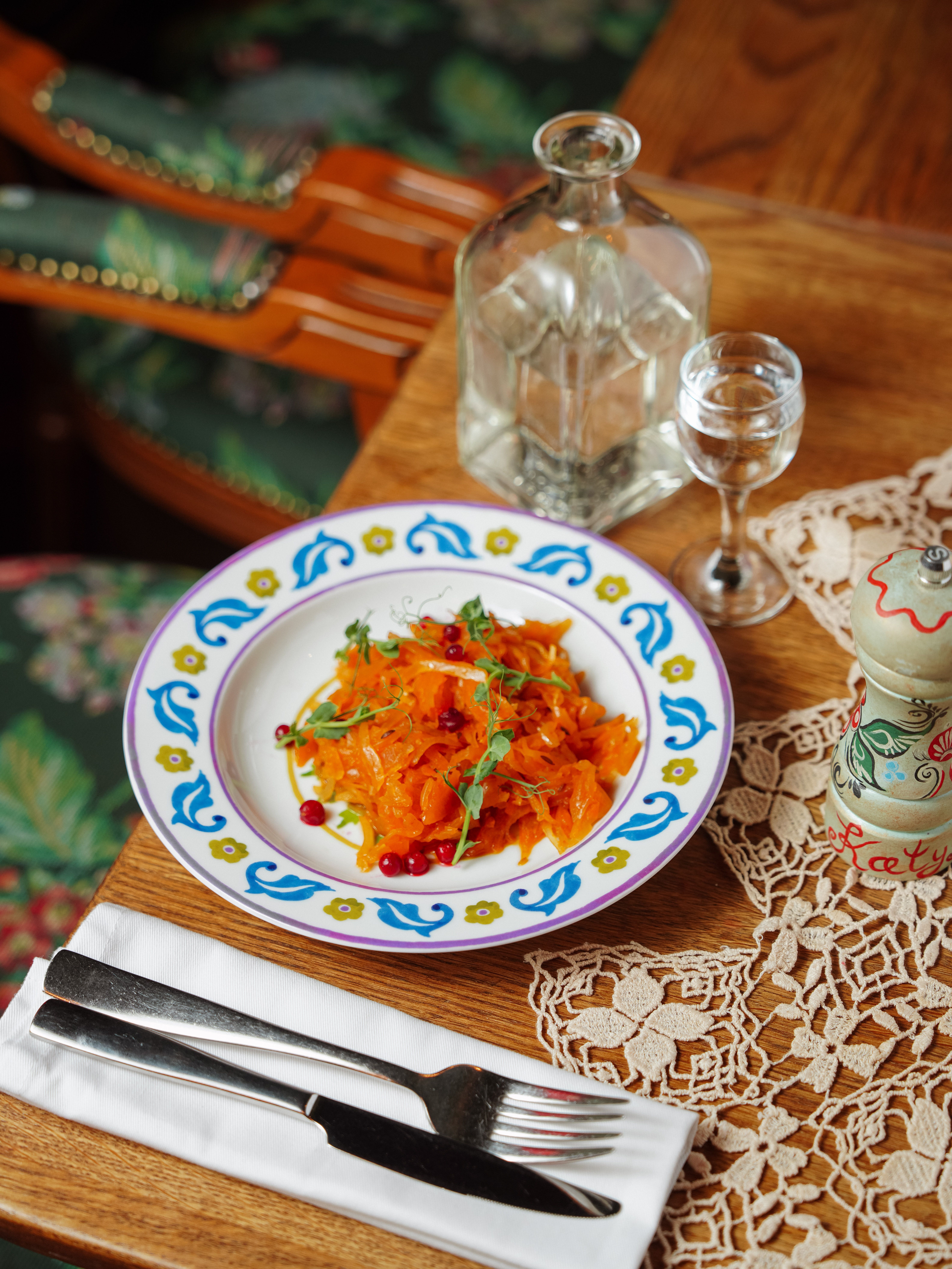 A vibrant carrot salad garnished with arugula and berries on a rustic table.