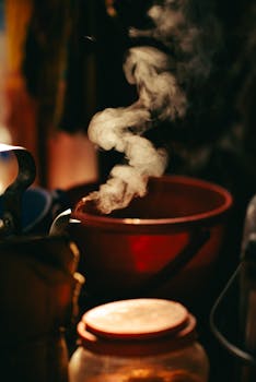 Close-up of steam rising from a pot in a warmly lit kitchen environment.