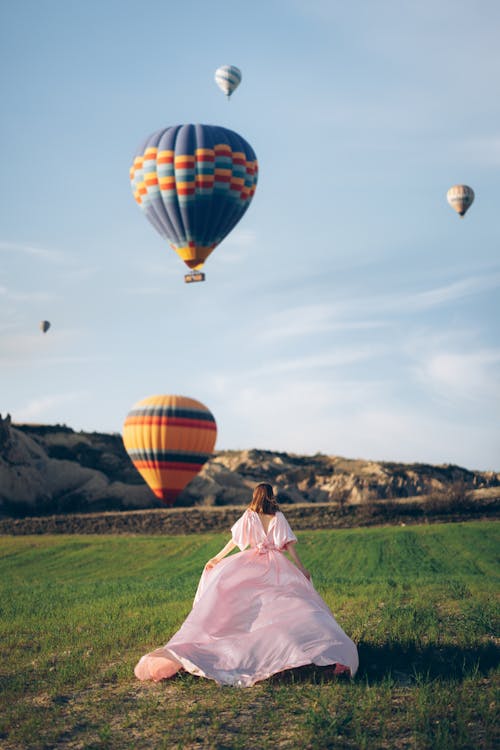 Woman in Dress Posing with Balloons Flying on Clear Sky