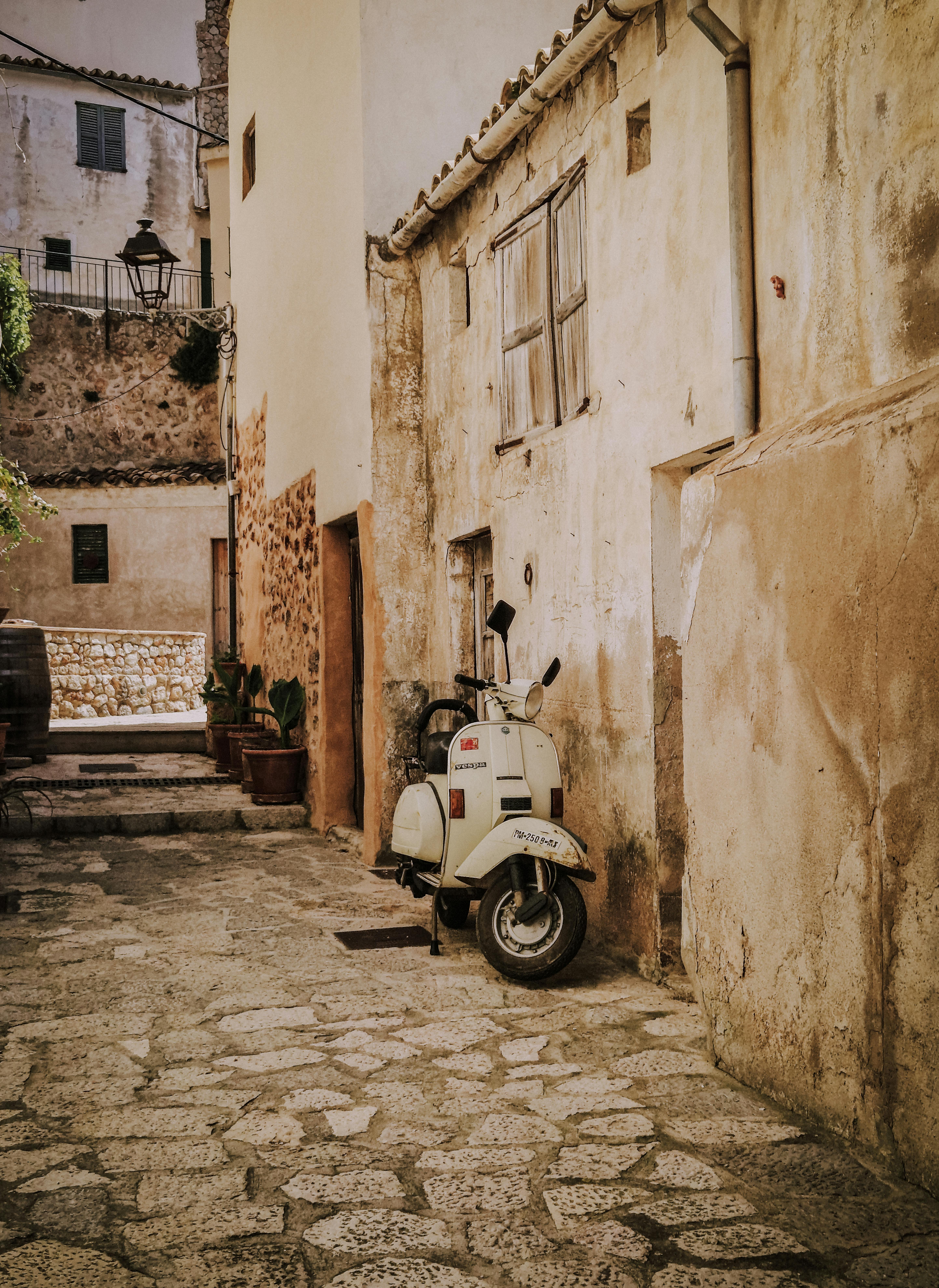 Old Vespa parked on a cobblestone street in Palma, Spain, exuding vintage European charm.