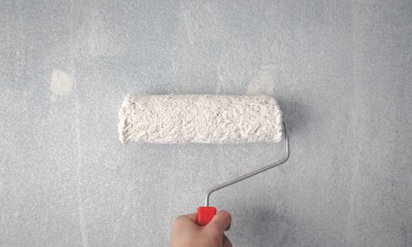 Painter & Decorator โ A person's hand using a paint roller to apply white paint on a wall.