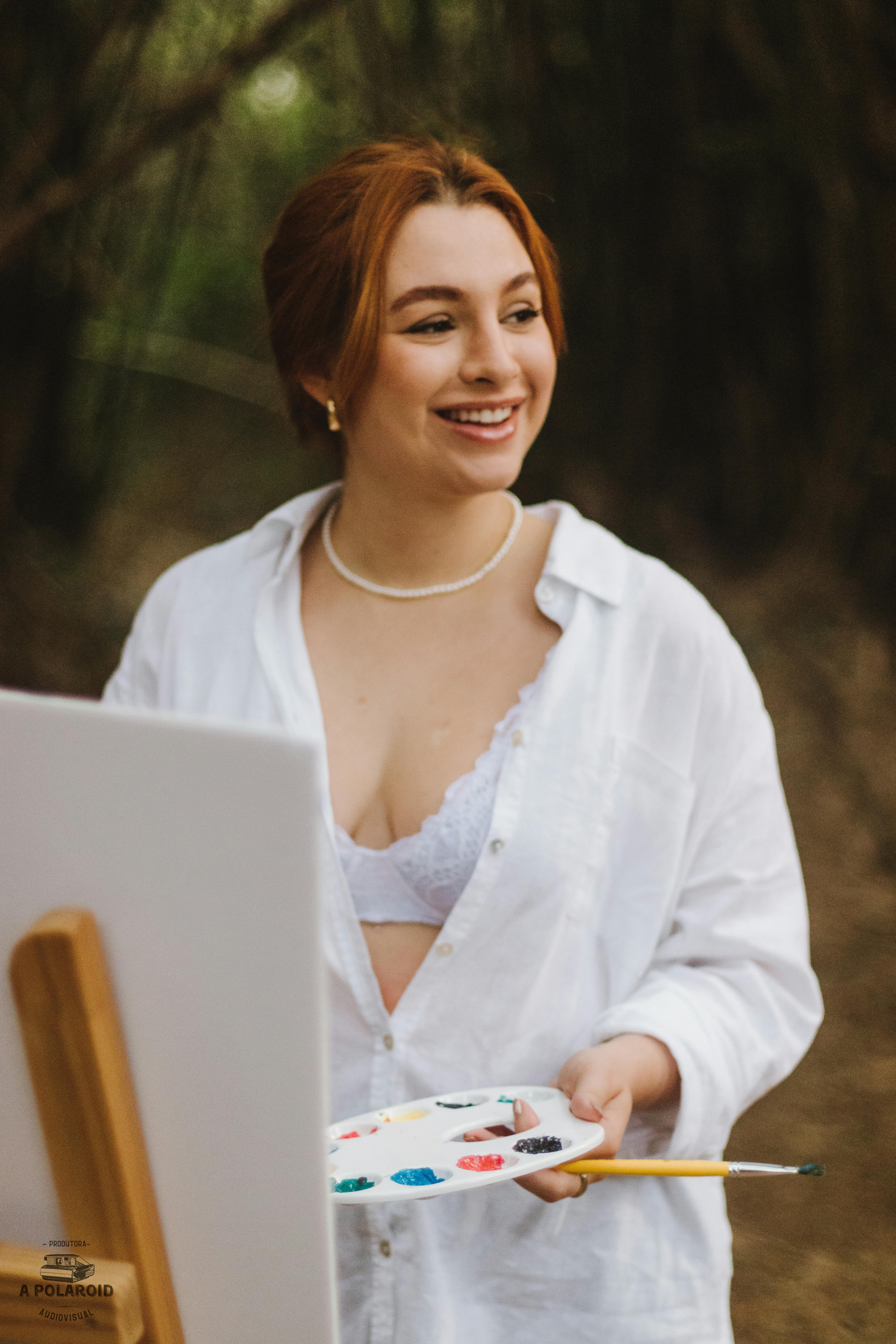 A young woman artist with a paint palette and canvas in a natural setting.