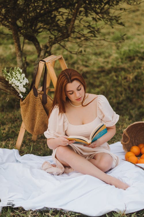 Woman Sitting in Summer Garden Reading Book