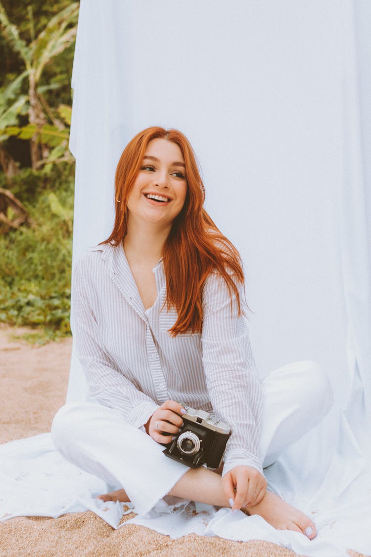 Smiling Redhead Woman With Retro Camera Posing On White Fabric Outdoors