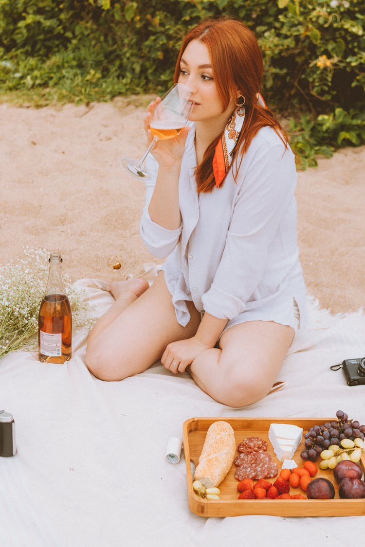 Redhead Woman Drinking Wine On Picnic On Beach