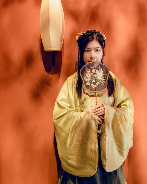 Woman in Traditional Clothing Posing with Decorated Fan
