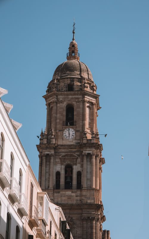 Free View of the iconic cathedral tower in Málaga, Spain, under a clear blue sky. Stock Photo