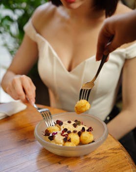 Woman enjoying a stylish appetizer in an elegant setting, highlighting fashion and gourmet food.