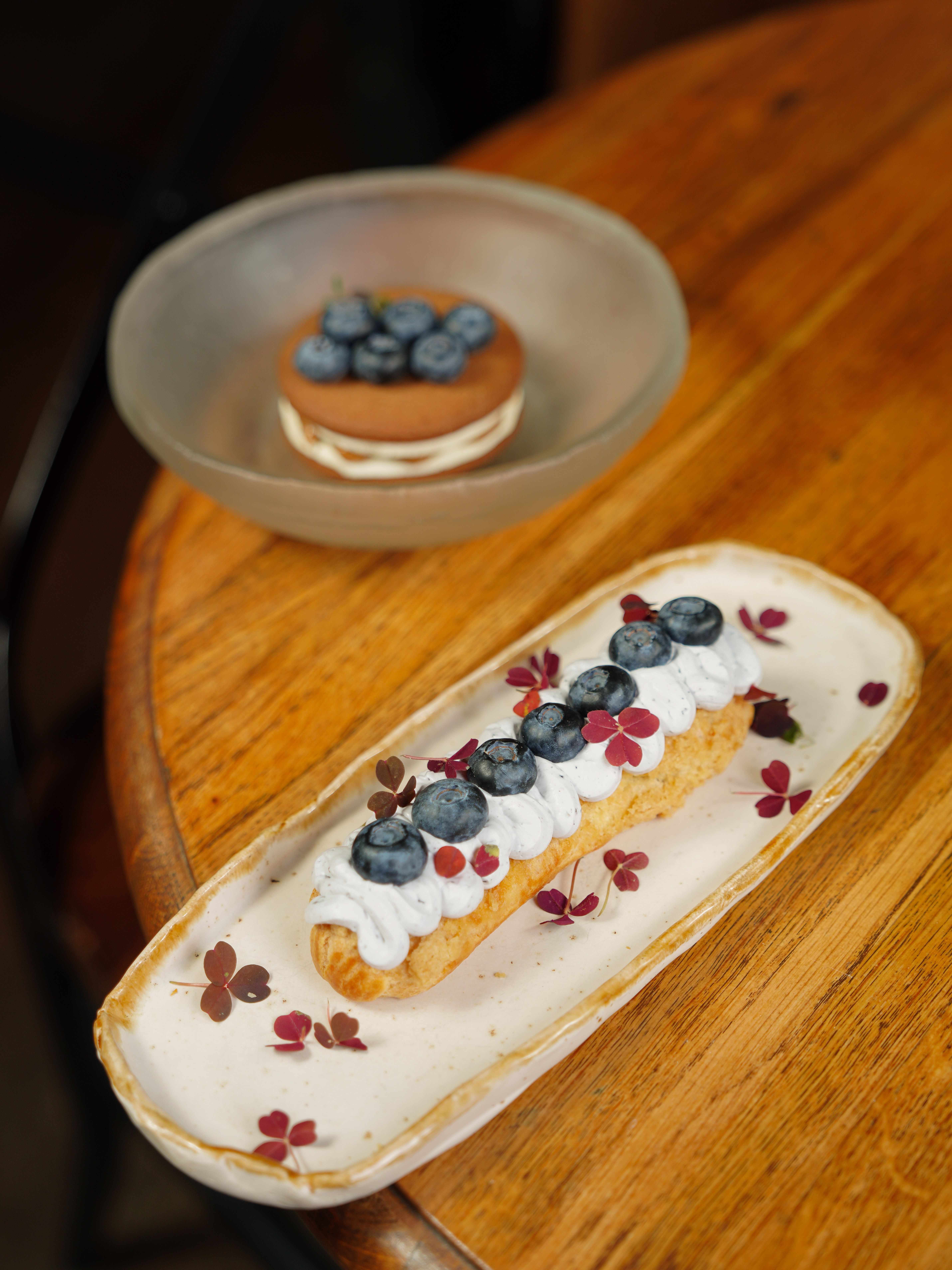 Tasty eclair topped with fresh blueberries and cream, perfect for dessert lovers.