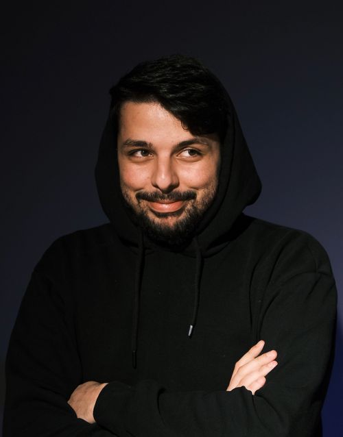 Free Portrait of a young man with black hair, smiling in a studio setting while wearing a hoodie. Stock Photo