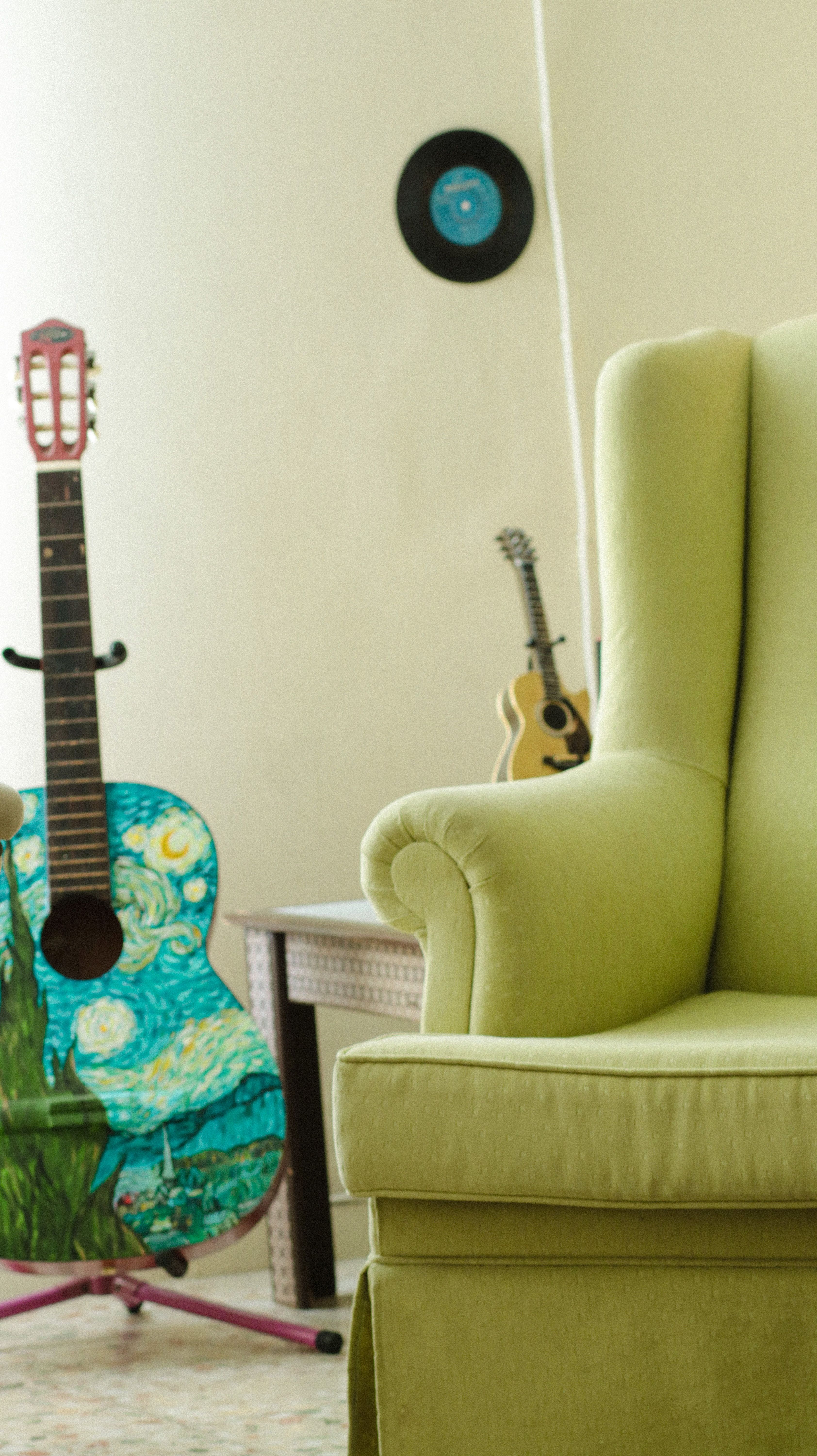 Cozy living room interior showcasing artistic guitars and a comfortable green sofa.