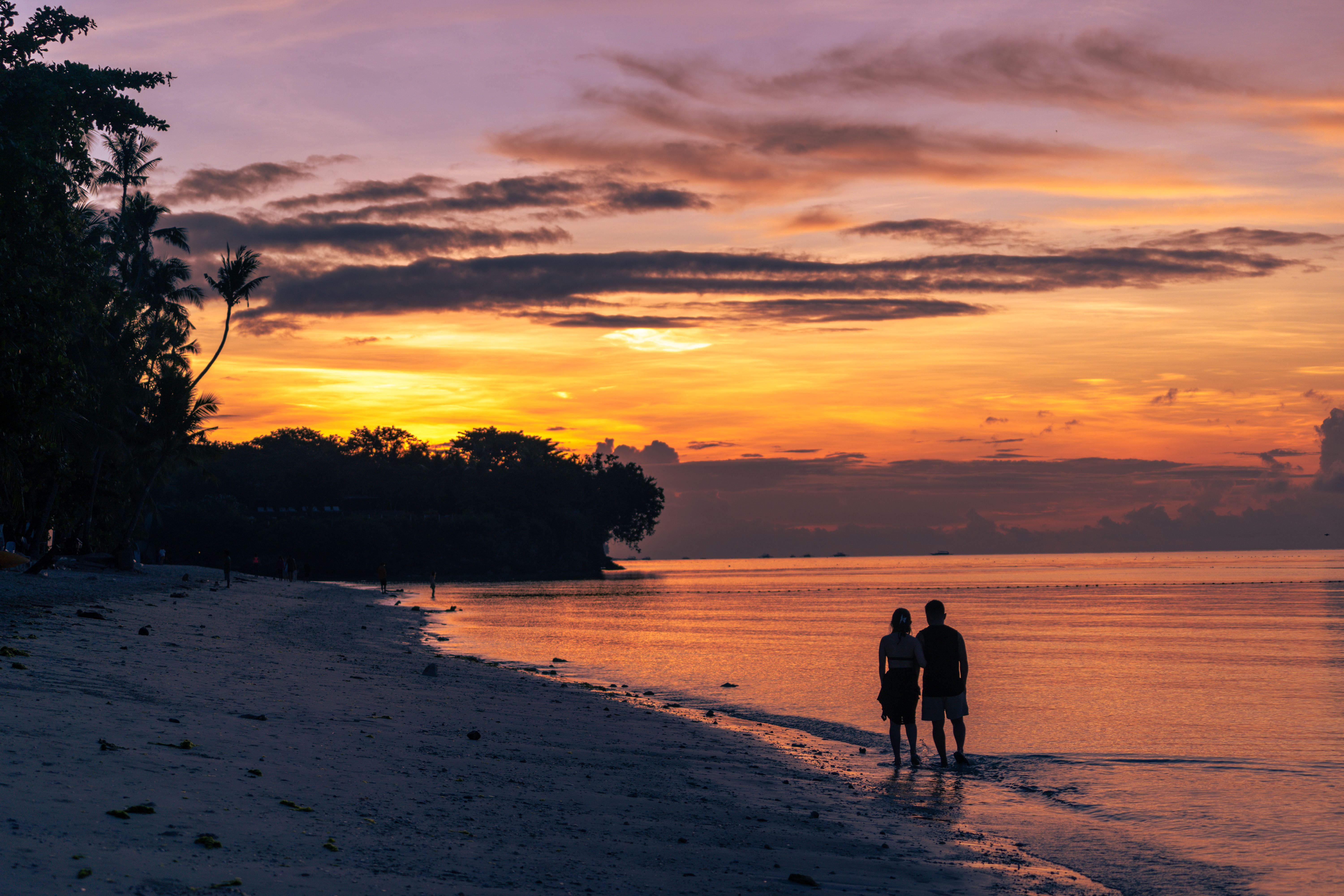 Couple walking along a beautiful beach at sunset, enjoying a dream retirement travel experience