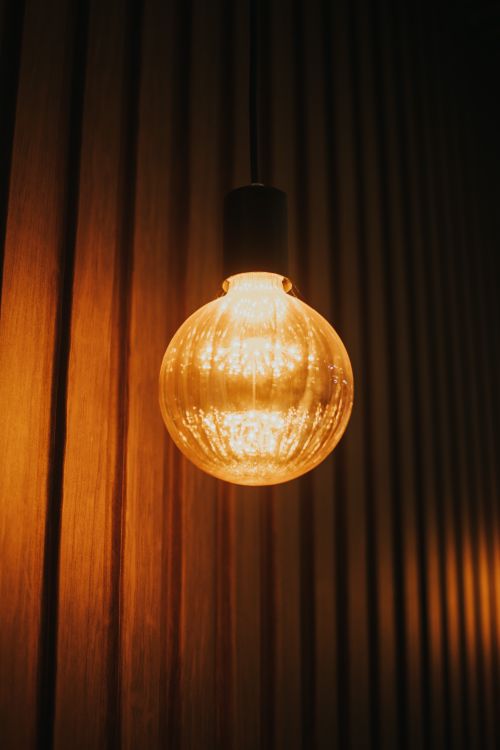 Free Warmly lit Edison bulb against a wooden slat wall. Perfect for rustic interior design concepts. Stock Photo