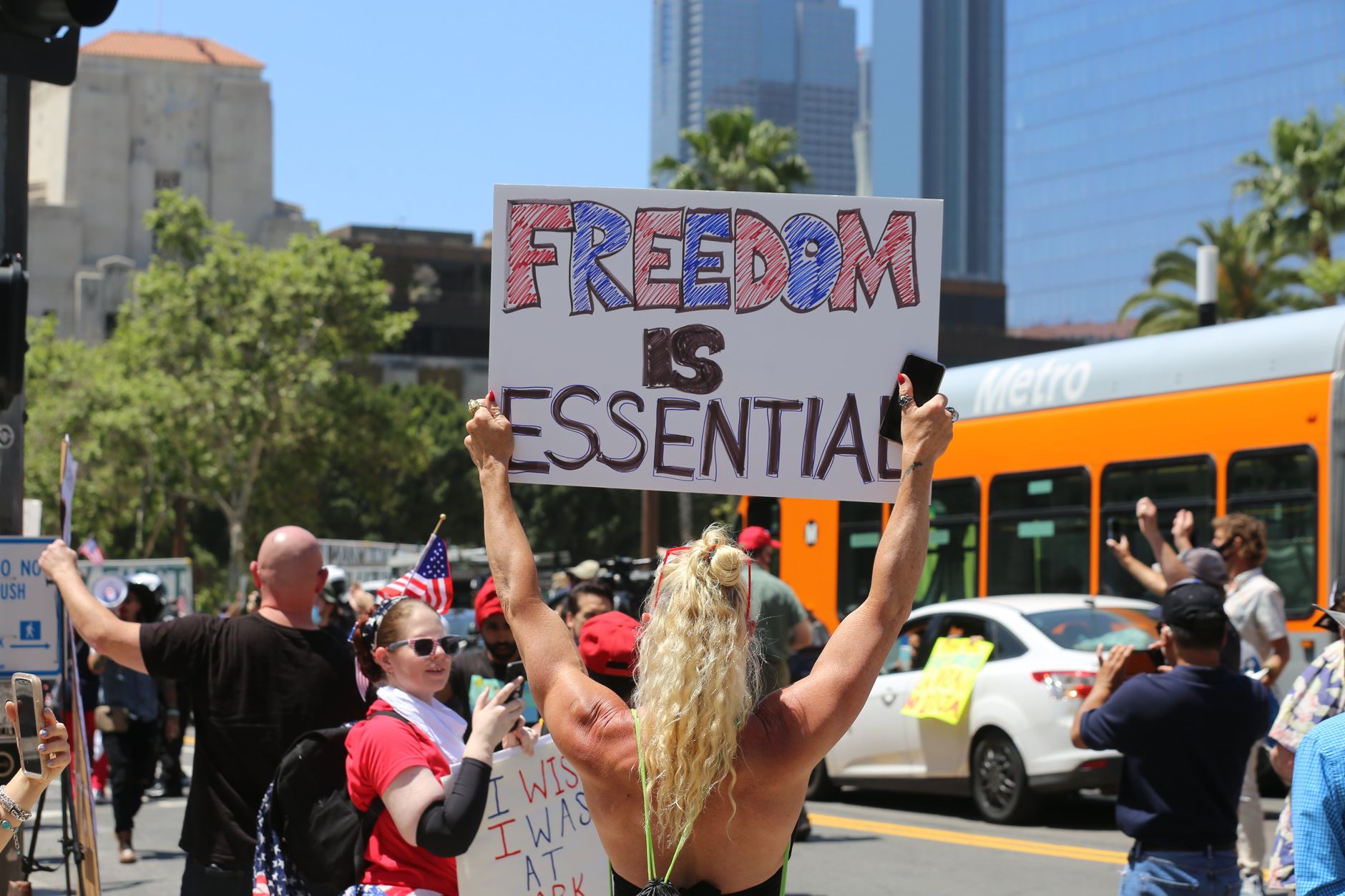 A protester holds a 'Freedom is Essential' sign during a city rally, advocating for social issues.
