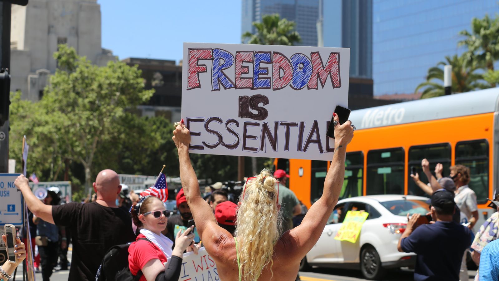 A protester holds a 'Freedom is Essential' sign during a city rally, advocating for social issues.