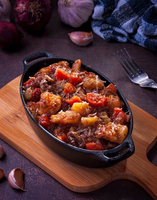 Free Delicious homemade beef stew with vegetables in a black cast iron dish on a wooden board. Stock Photo