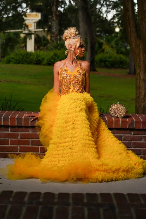 Woman in Yellow Dress Sitting on Wall at Park