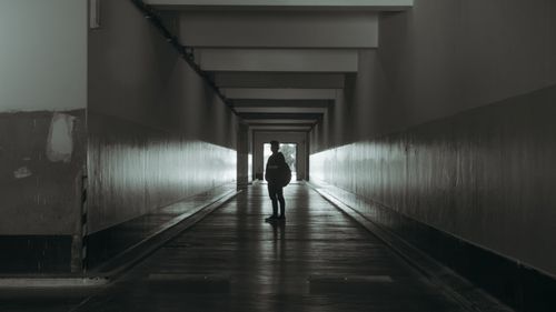 Free Moody silhouette of a person standing alone in a dimly lit urban tunnel. Stock Photo