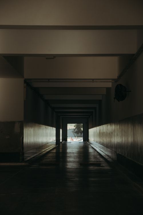 Free Dark urban corridor with natural light at the end, creating a dramatic atmosphere. Stock Photo