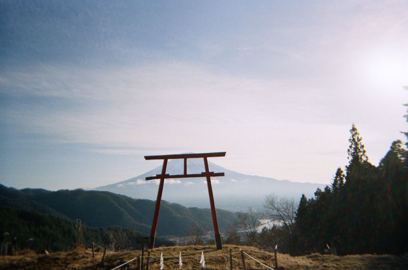 Tenku no Torii at Kawaguchi Asama Shrine, Yamanashi — solitary torii gate on a hillside above Lake Kawaguchiko with Mount Fuji in the background