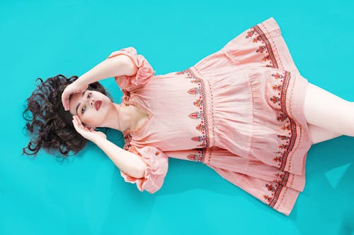Young woman in a Dress Lying on Blue Background 