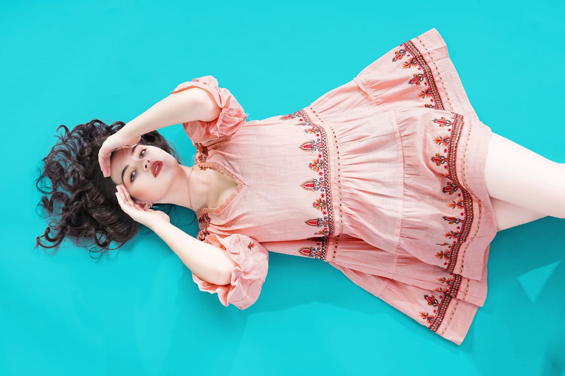 Young woman in a Dress Lying on Blue Background 