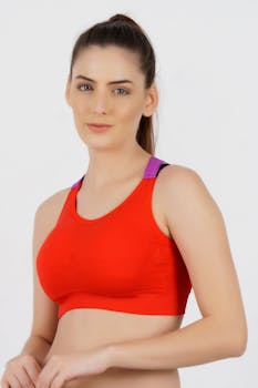 Portrait of a woman in a red sports bra against a white background, conveying confidence and style.