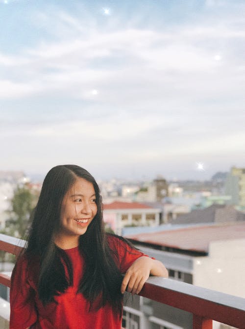 Smiling Woman Leaning on Balcony Fence