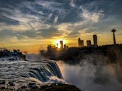 尼亚加拉大瀑布的日落景观充满戏剧性，城市天际线轮廓与朦胧的瀑布相映成趣