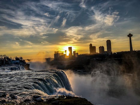 尼亚加拉大瀑布的日落景观充满戏剧性，城市天际线轮廓与朦胧的瀑布相映成趣
