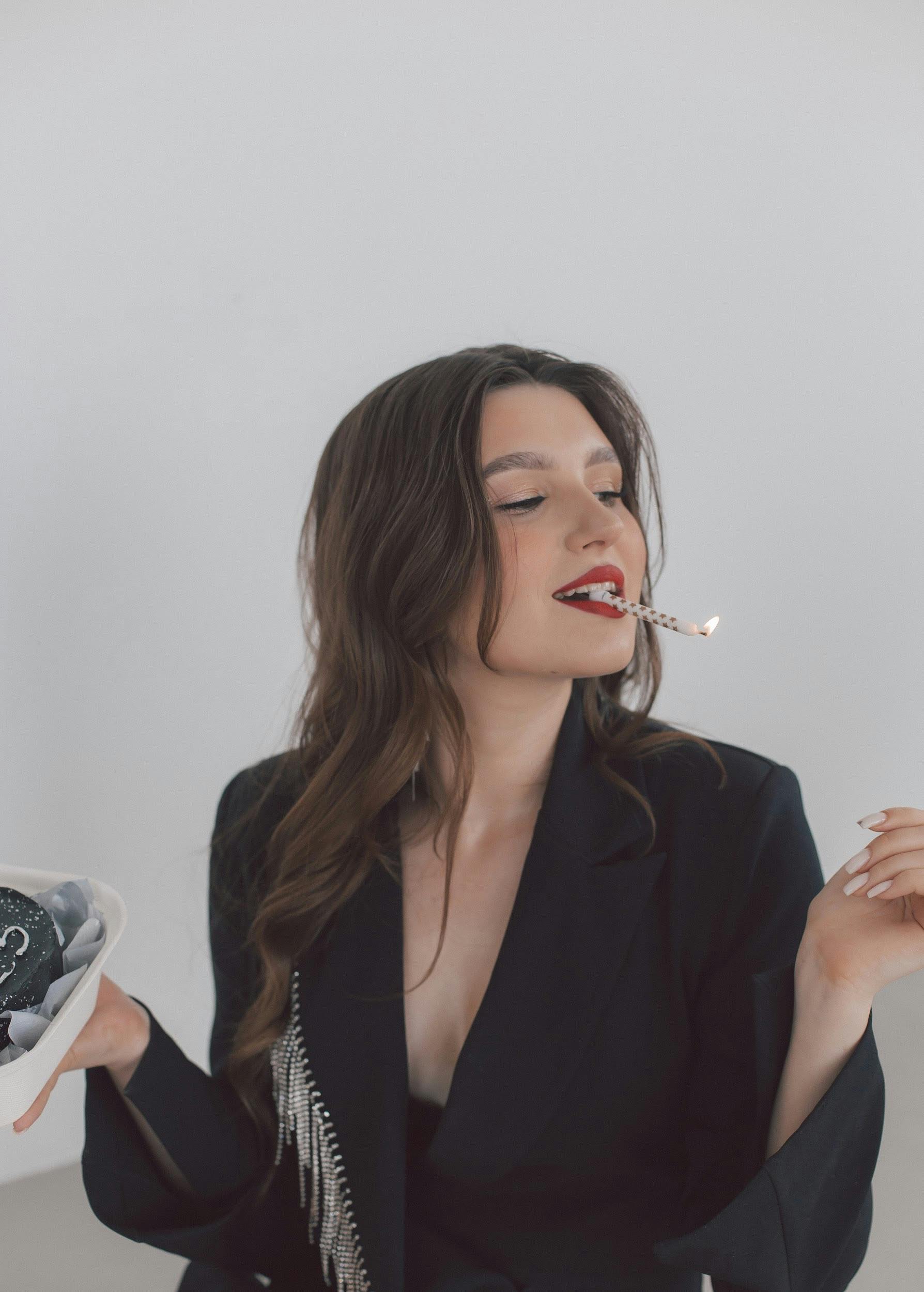 young woman holding a birthday candle in her mouth like a cigarette