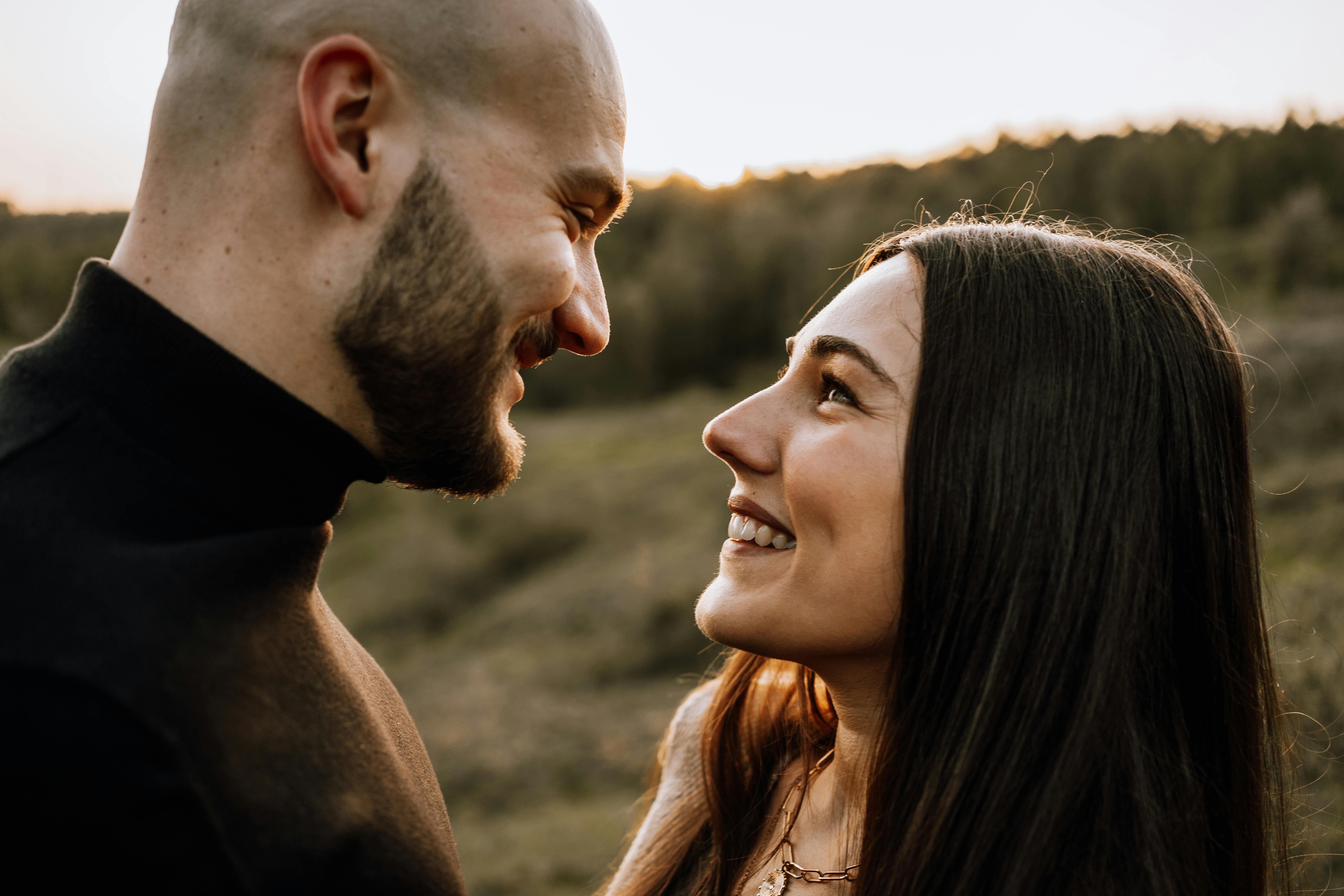 Couple lost in each other's eyes as golden sunset light glows behind them.