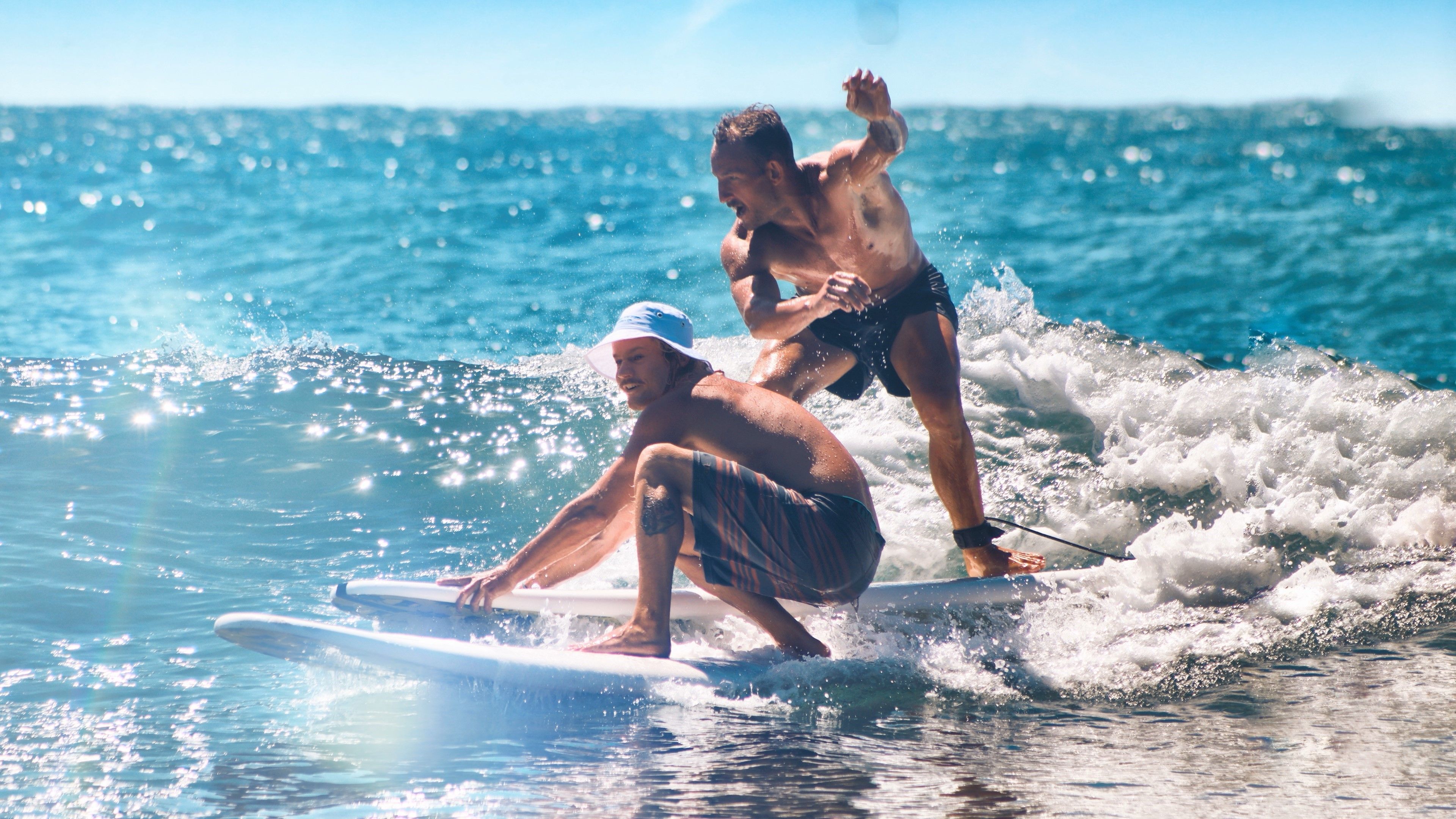 Two men skillfully surfing on a sunny day, capturing the excitement of the ocean waves.