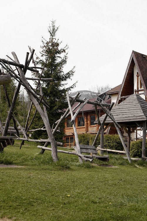 Wooden Swings in the Yard next to Traditional Houses in Mountains 