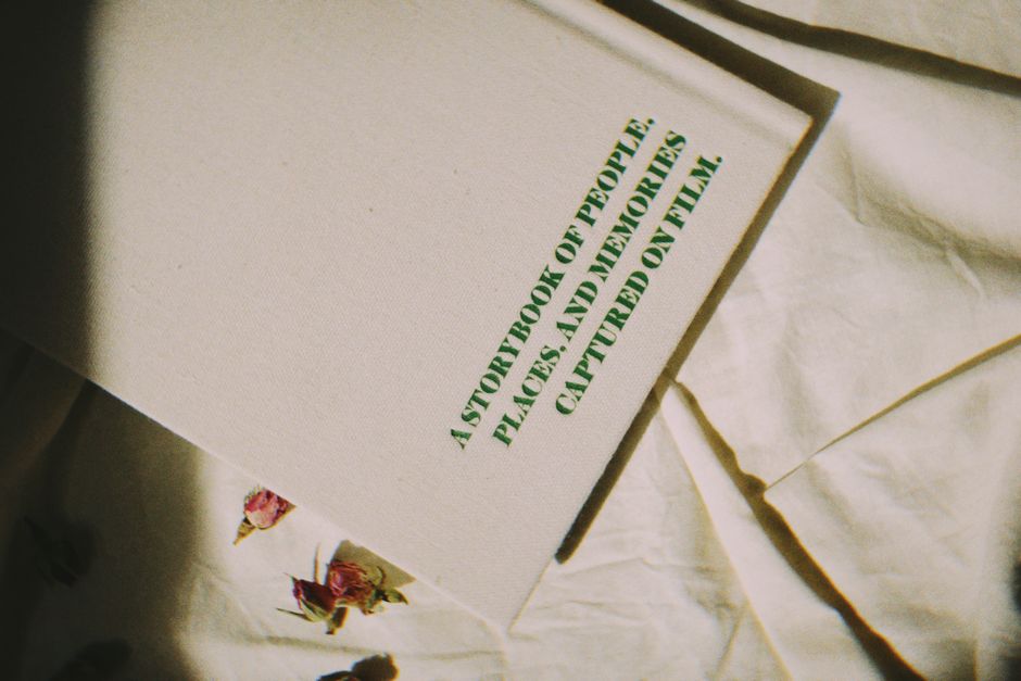 A book cover with text resting on a white fabric decorated with dried flowers.
