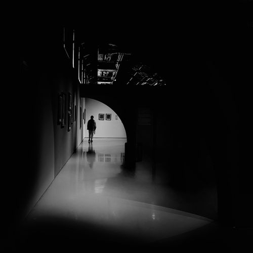 Free A lone figure walks through a dimly lit modern urban corridor. Stock Photo