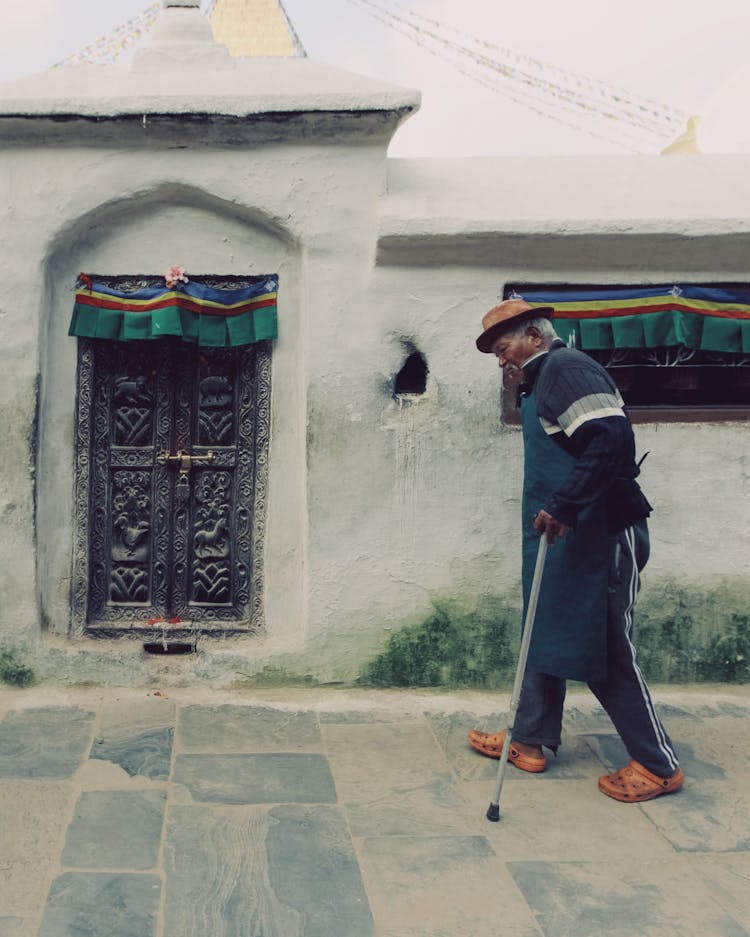 Elderly Man In Hat Walking With Walking Stick