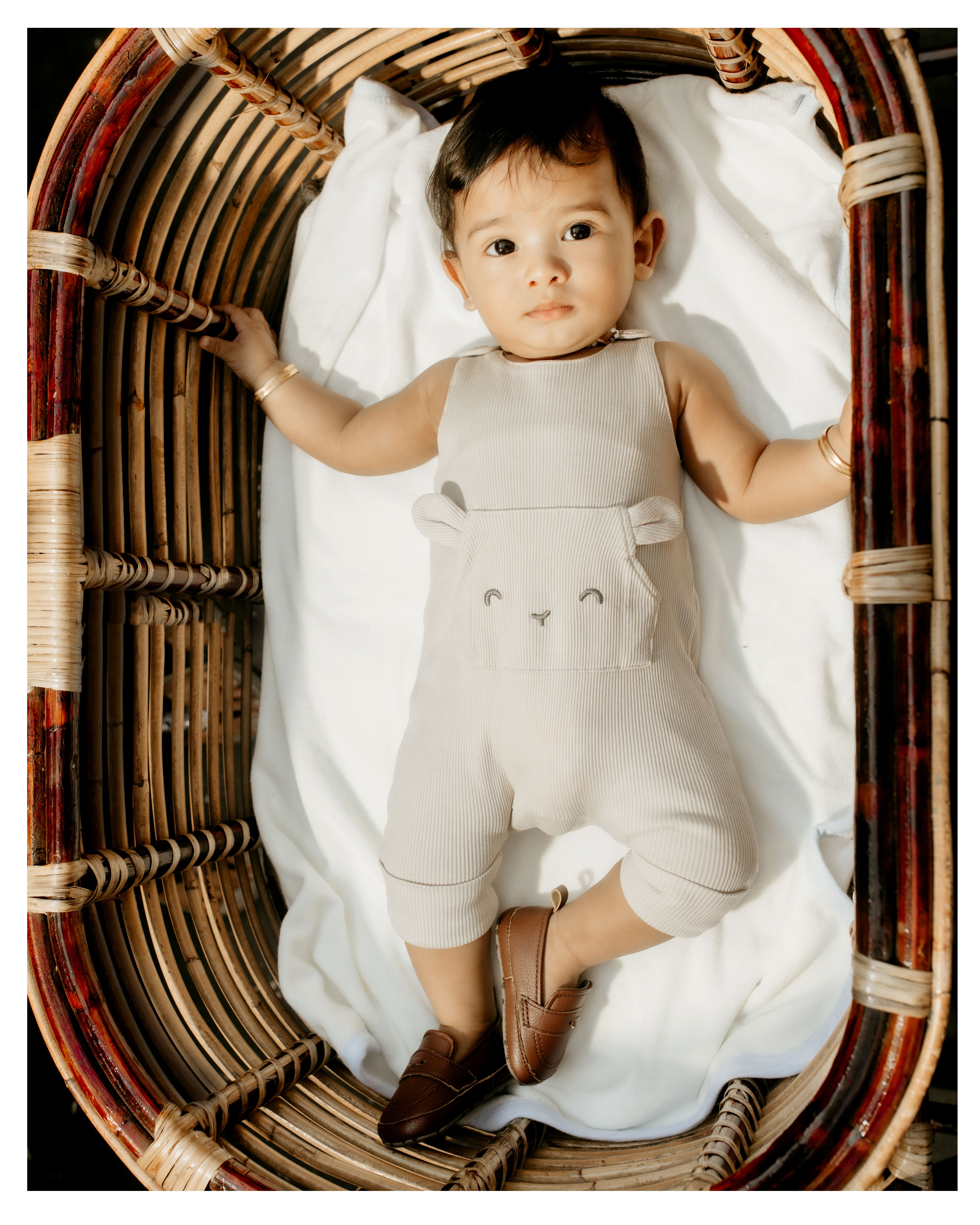 Charming baby lying in a basket, wearing cute animal-themed overalls. Perfect child fashion photography.