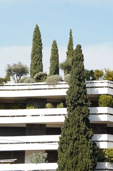 Iconic modern building in Athens with lush green trees and clear blue sky.