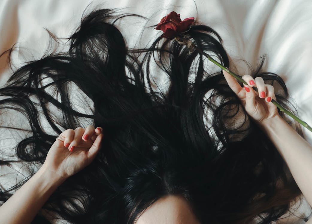 Free Woman Lying on Bed With Rose on Her Hand Stock Photo