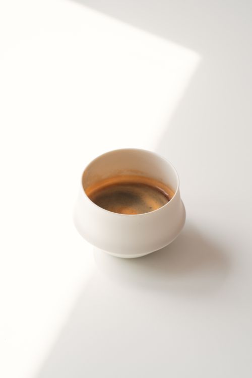 Free A high-angle view of a simple white cup filled with rich espresso on a bright surface. Stock Photo