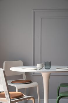 Stylish minimalist dining area with elegant chairs and a round table in soft lighting.