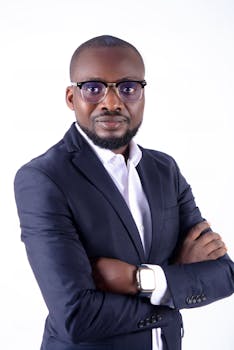 Portrait of a confident businessman wearing a black suit, eyeglasses, and watch on white background.