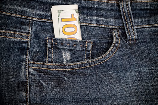 Close-up of blue denim jeans with a $100 bill in the pocket, symbolizing financial savings.